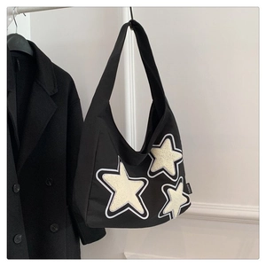 Detail of black canvas hobo bag with white plush stars and fashion side label