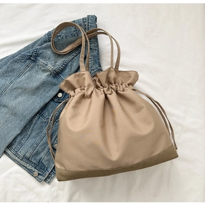 Detailed view of the drawstring closure and durable brown base of the beige shoulder bag