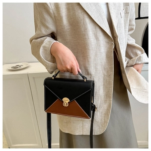 Détail du sac enveloppe bicolore avec coutures contrastées et fermoir rotatif en métal