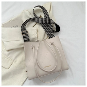 Détail du sac fourre-tout crème matelassé avec bandoulière pied-de-poule et logo mode