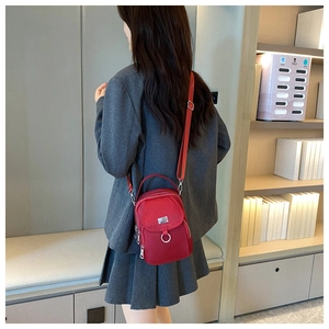 Red Oxford fabric crossbody bag shown on a model with multi-layer zipper pockets