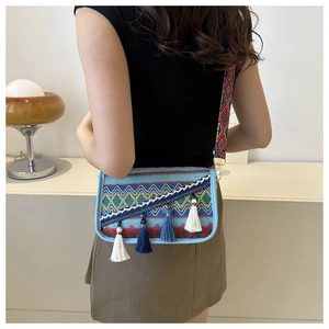 Detailed shot of ethnic woven crossbody bag featuring colorful tassels and embroidered strap