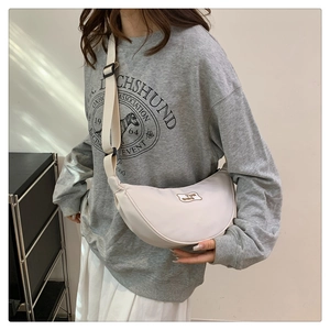 Detail view of cream crescent crossbody bag with adjustable wide strap and logo patch