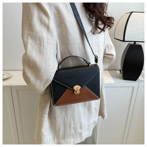 Détail du sac enveloppe bicolore montrant le fermoir doré et les coutures blanches