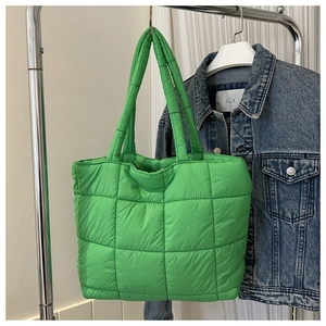 Detail of bright green quilted puffer bag hanging with a denim jacket background