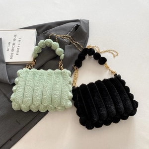 Detail of plush faux fur tote bags in mint green and black with gold chain straps