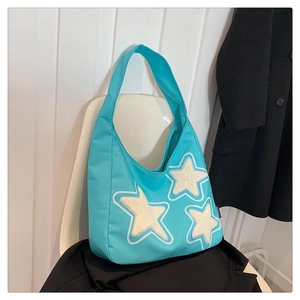 Blue canvas tote bag on a chair featuring three decorative white plush star patches