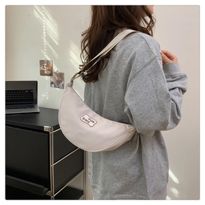 Close-up of cream crescent crossbody bag featuring wave edge patch and Yun Qing text