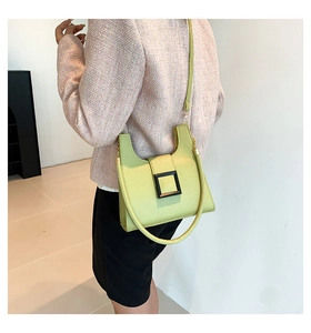 Detail of avocado green crossbody bag featuring litchi grain texture and black square buckle