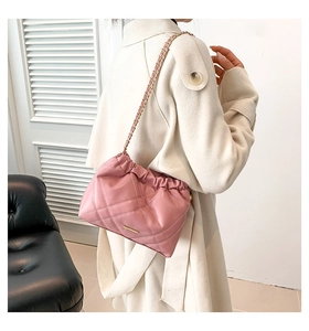 Detail of pink quilted bucket bag with gold chain strap and elegant fold design