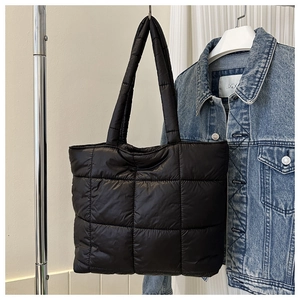 Detail of black quilted tote bag with large square stitching and puffer design