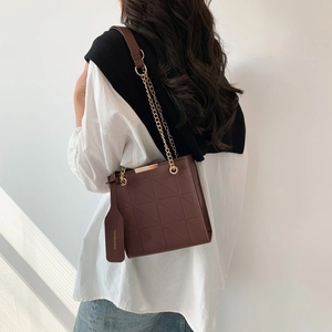 Detail of brown quilted rhombic texture shoulder bag with gold chain and leather tag