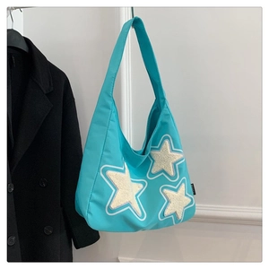 Detail of teal canvas tote bag featuring soft white plush star embroidery and side label