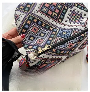Close-up of smooth gold metal zipper and colorful ethnic woven fabric on women's bag