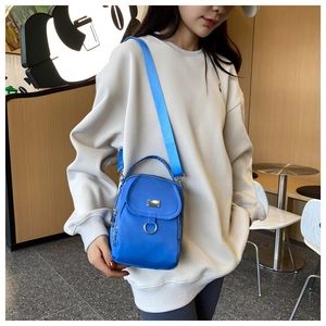 Detail of blue nylon crossbody bag featuring metal ring and front zipper pocket