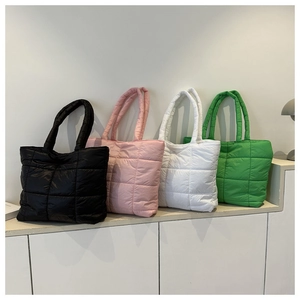 Quilted puffer tote bags in black, pink, white, and green displayed on a minimal counter