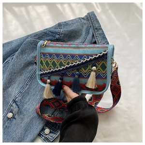 Detail of colorful woven crossbody bag featuring ethnic geometric patterns and stylish tassels