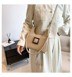 Detail view of stylish khaki crossbody bag with square buckle and metal chain strap