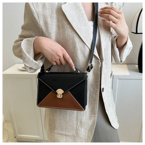 Détail du sac à bandoulière contrasté avec fermoir doré et fines coutures blanches