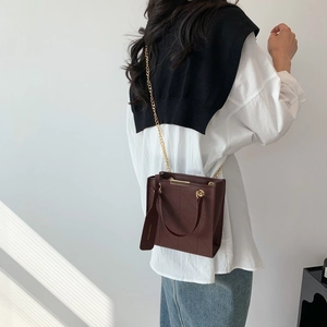 Detailed view of dark brown quilted crossbody bag with gold chain strap worn by a model