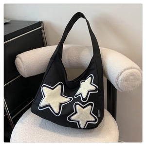 Close-up of black nylon crescent tote bag featuring plush white star patches and side label
