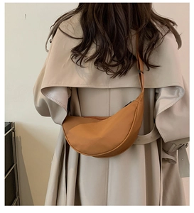 Dettaglio della borsa a mezzaluna giallo zenzero su un trench coat beige chiaro