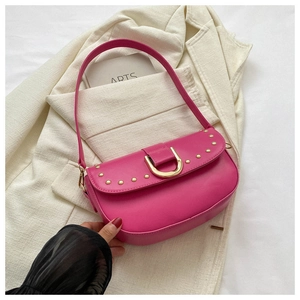 Détail du sac selle en cuir rose fuchsia avec boucle fer à cheval dorée et rivets en métal