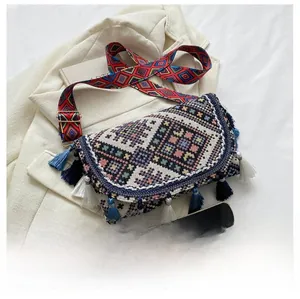 Detailed view of bohemian woven crossbody bag with colorful tassels and patterned strap