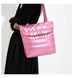 Detail of metallic pink quilted puffer tote bag with wide shoulder strap and glossy finish