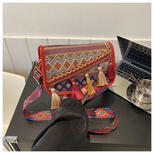 Detail view of ethnic style crossbody bag with colorful weaving and multi-color tassels