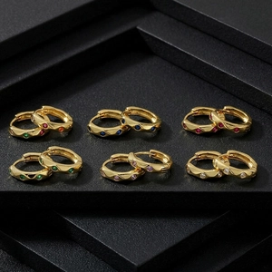 Close-up of golden huggie earrings with colorful inlaid stones on black display stand