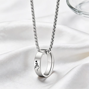 Silver necklace with ring pendant featuring finger heart engraving on white silk background