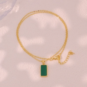Detailed close-up of a golden necklace featuring a rectangular green malachite pendant