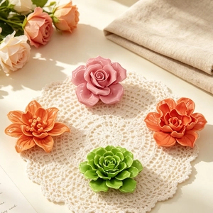 Floral ceramic home ornaments in pink and orange glaze on a lace cloth with roses