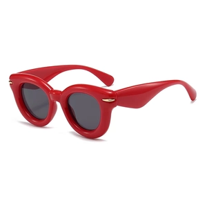 Detail view of retro red frame sunglasses with golden metal accents on the corners