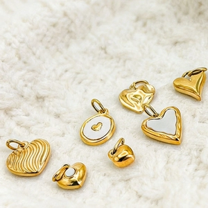 Golden heart pendants in various designs with 14K gold plating on textured fabric
