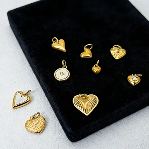 Detailed view of 14K gold heart pendants with various textures and pearl shell inlays