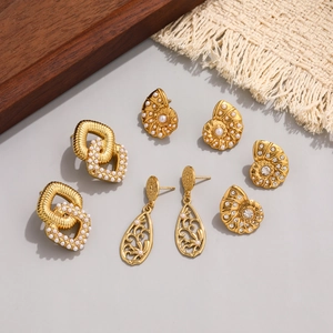 Detail of assorted golden earrings with pearls and rhinestones on elegant tabletop