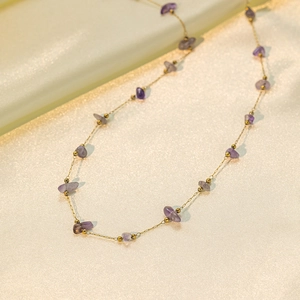 Irregular purple stone gold chain necklace on elegant yellow silk background