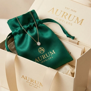 Close-up of golden necklace with crystal pendant in green satin pouch and premium gift box