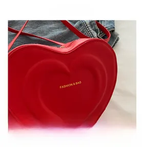 Detailed macro view of red heart-shaped shoulder bag with embossed fashion text and zipper