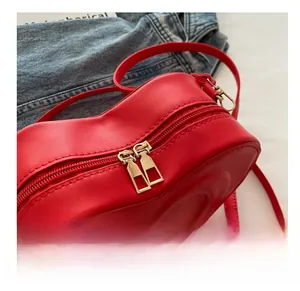 Close-up of red heart shaped bag with dual gold zippers and matte leather texture