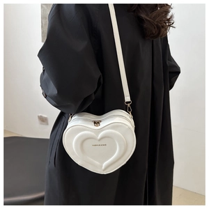 Detail of white heart-shaped crossbody bag with embossed texture and metal zipper