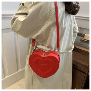 Detail of red heart-shaped crossbody bag featuring multi-layer embossed leather textures