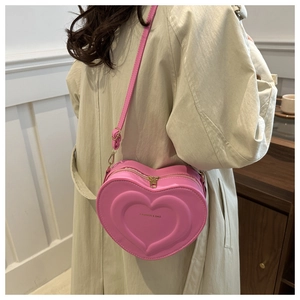 Detail showing pink heart-shaped crossbody bag with quilted texture and gold hardware