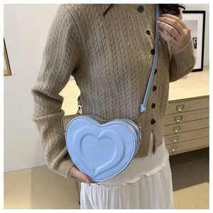 Close-up of light blue heart-shaped bag featuring concentric embossed textures and golden logo