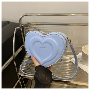 Detail showing light blue heart-shaped leather handbag with embossed concentric pattern