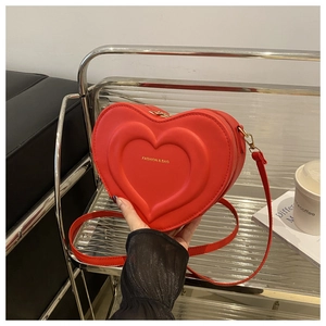 Detail of red heart-shaped shoulder bag featuring layered 3D relief and golden zipper