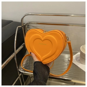 Detail view of orange heart-shaped crossbody bag with embossed layers and gold hardware