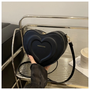 Close-up of heart-shaped black leather bag with layered 3D design and gold lettering